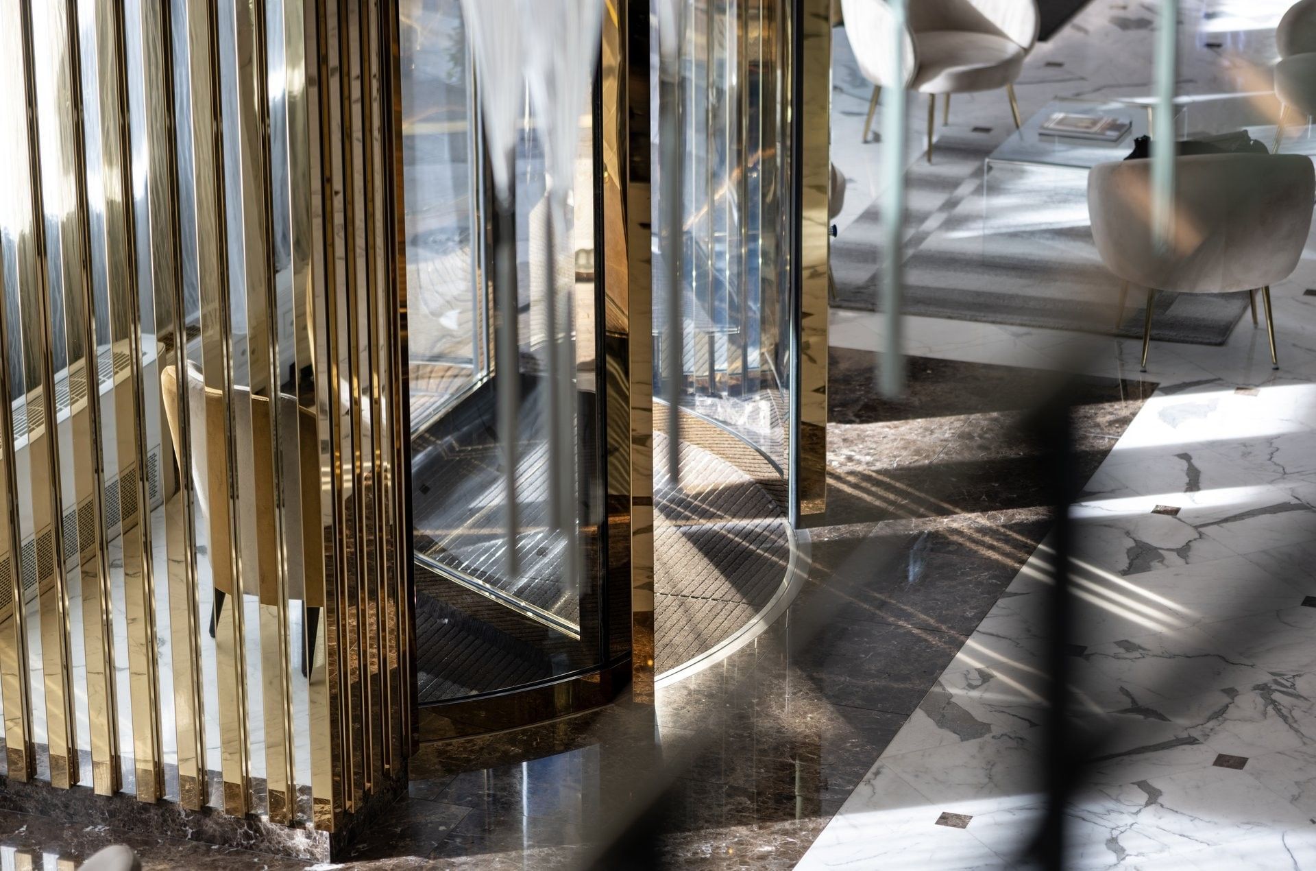 Tan chairs by a black table under glass pendant lights near a gold elevator at Warwick Geneva