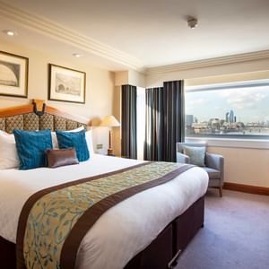 King bed & desk with a city view in a Room at Guoman Hotels