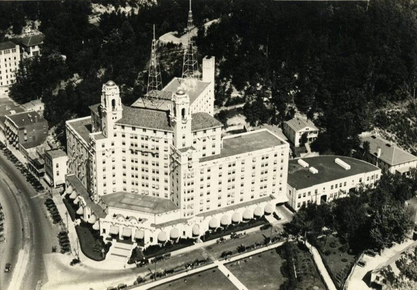 Vintage aerial view of Arlington Resort Hotel & Spa with twin towers, roads, and gardens surrounded by dense woodland