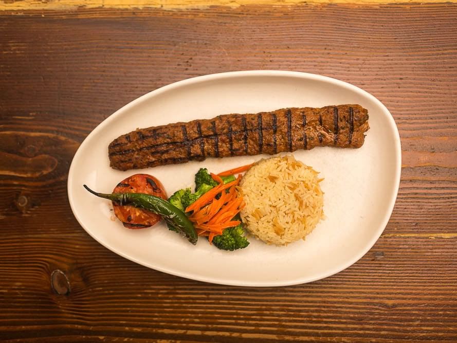 Plate of rice, vegetables, and meat on a wooden table from Pickwick San Francisco.