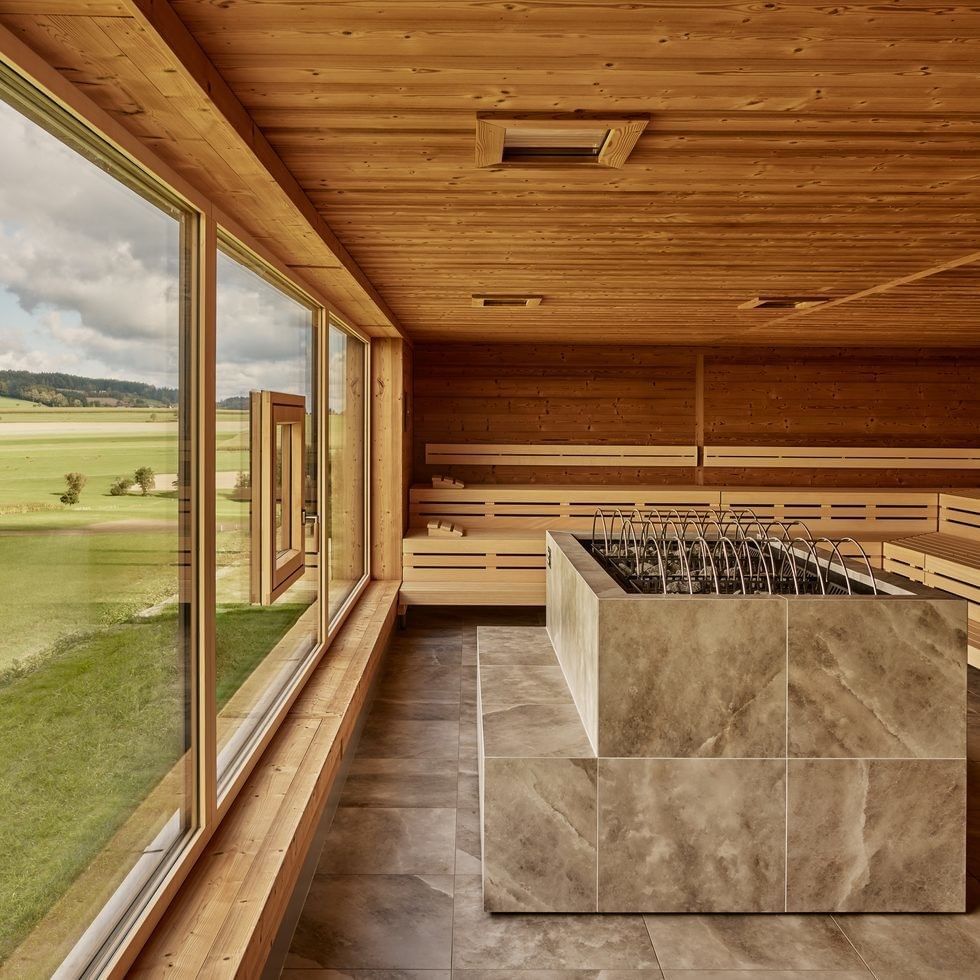 Moderne Sauna mit Holzverkleidung und Blick auf die grüne Landschaft.