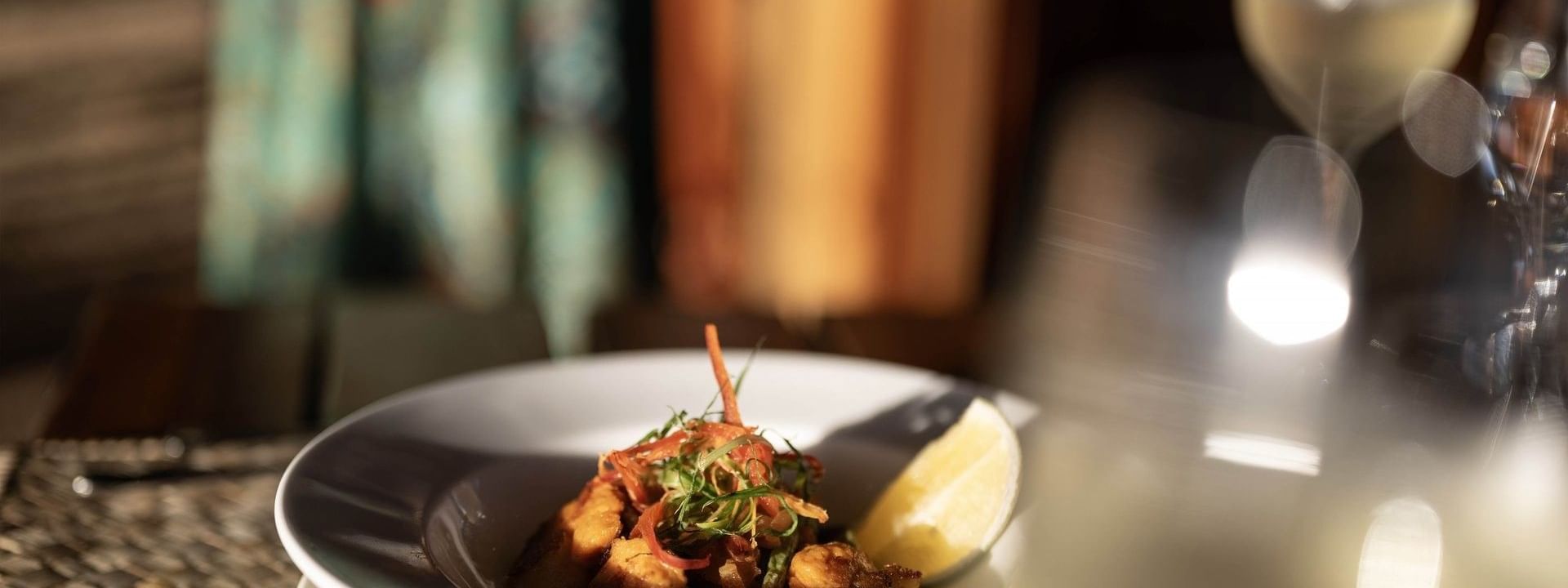 Gourmet dish with a lemon wedge by a wine glass in Wicked Walu at Warwick Fiji Resort and Spa