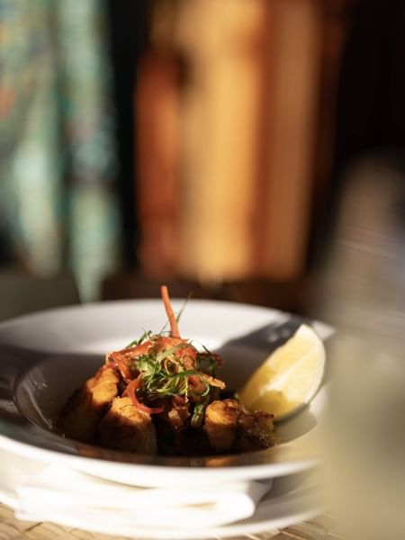 Gourmet dish with a lemon wedge by a wine glass in Wicked Walu at Warwick Fiji Resort and Spa