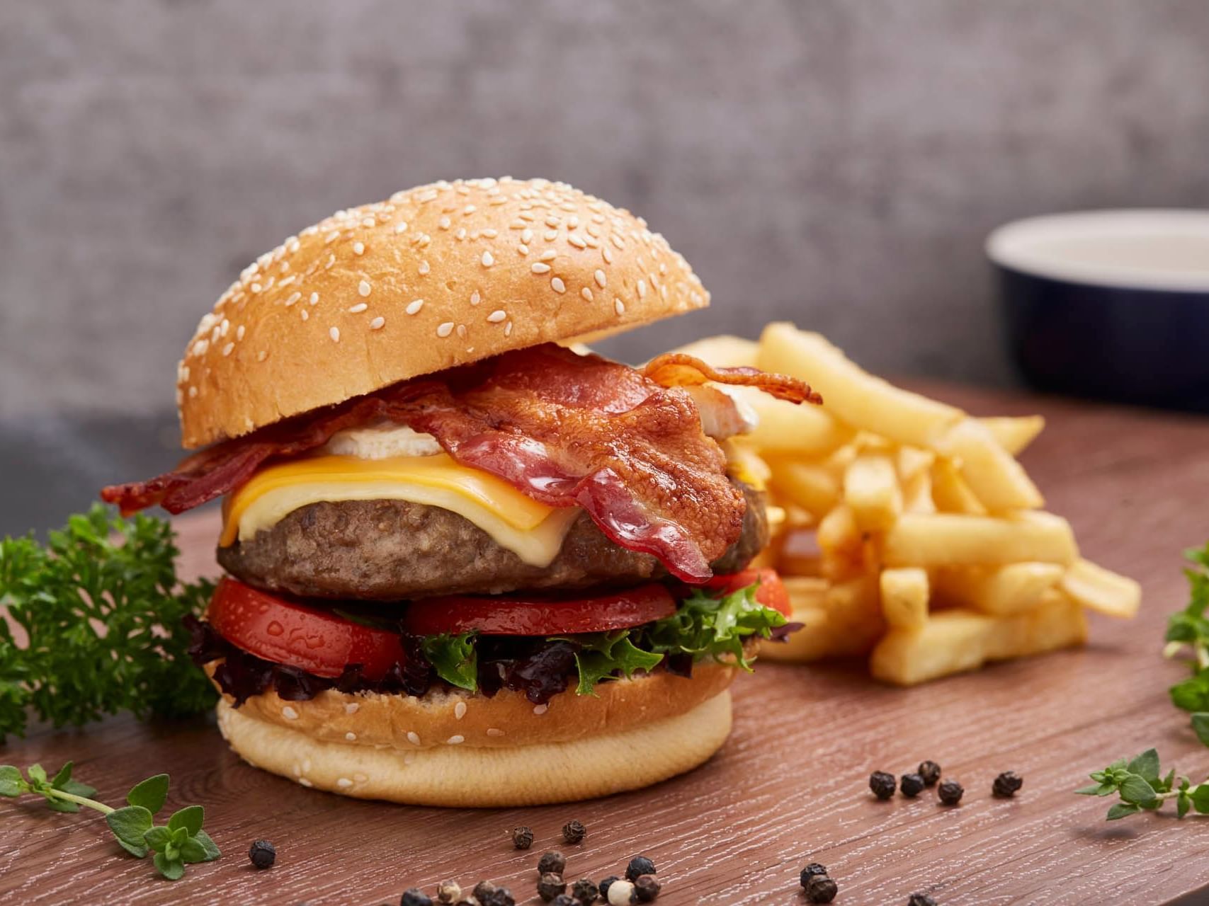 Ala Carte Beef Burger with bacon served with crispy fries on a wooden table at Crystal Café, Orchard Grand Court
