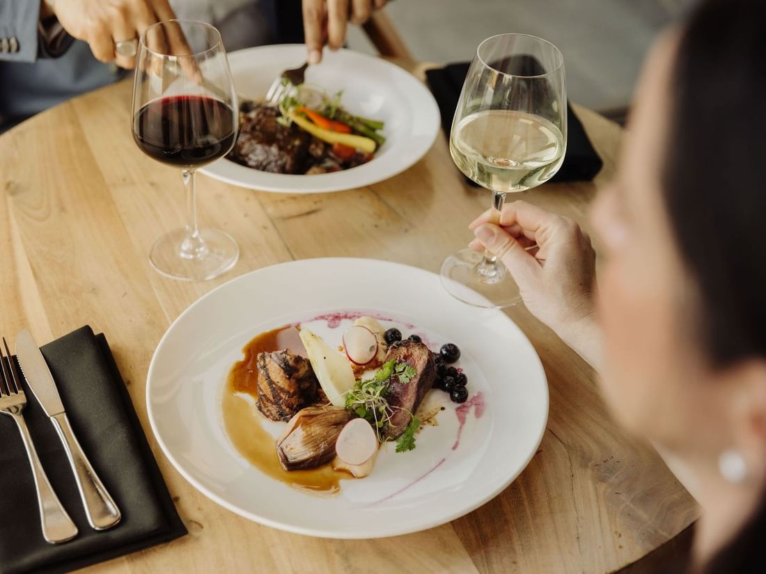 Gourmet dining scene with two diners at the Other Side of the Moon Restaurant & Bar, Pullman Bunker Bay Resort.