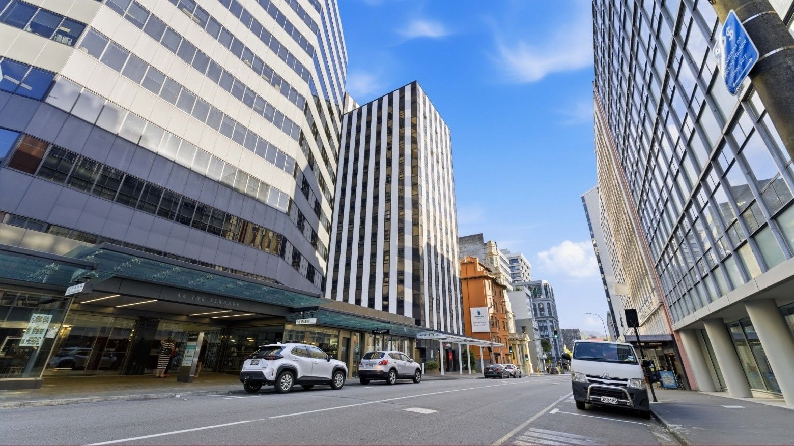 A city street with several cars parked outside a modern building at UniLodge Stafford House.