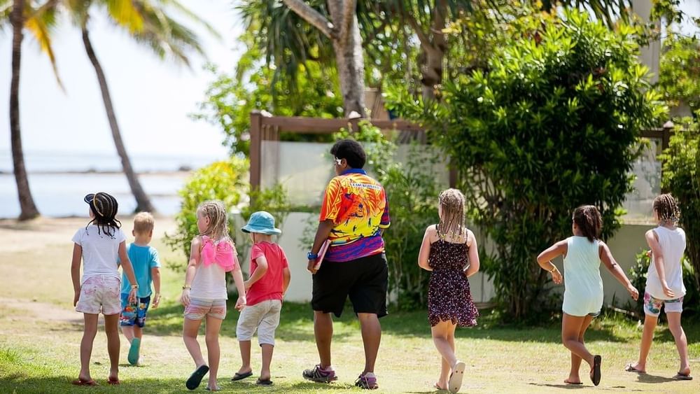 Children walking with an adult by the beach at The Naviti Resort in Korolevu.