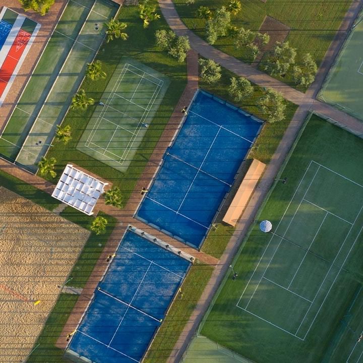 Luftaufnahme eines Sportkomplexes mit Tennisplätzen und Schwimmbecken.