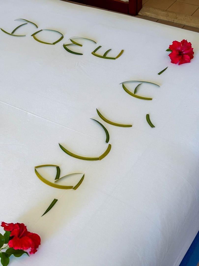 A neatly made bed with decorative leaves and red flowers spelling out Julie at The Naviti Resort in Korolevu, Fiji.