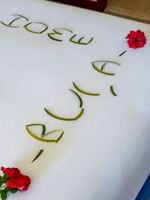 A neatly made bed with decorative leaves and red flowers spelling out Julie at The Naviti Resort in Korolevu, Fiji.