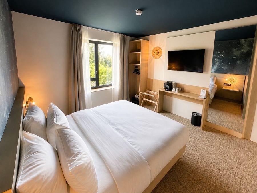 Suite Junior avec lit blanc et télévision chez Osmo Hôtel à Chantepie.