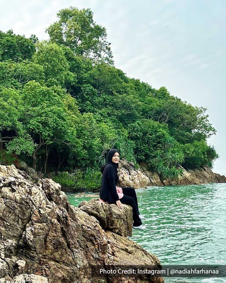 woman sitting on a rock with a forest view behind her