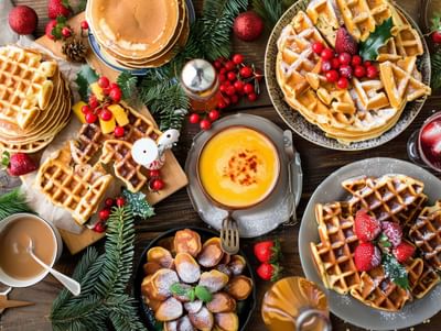 Breakfast spread featuring waffles and pancakes on a wooden table at Warwick Hotels and Resorts