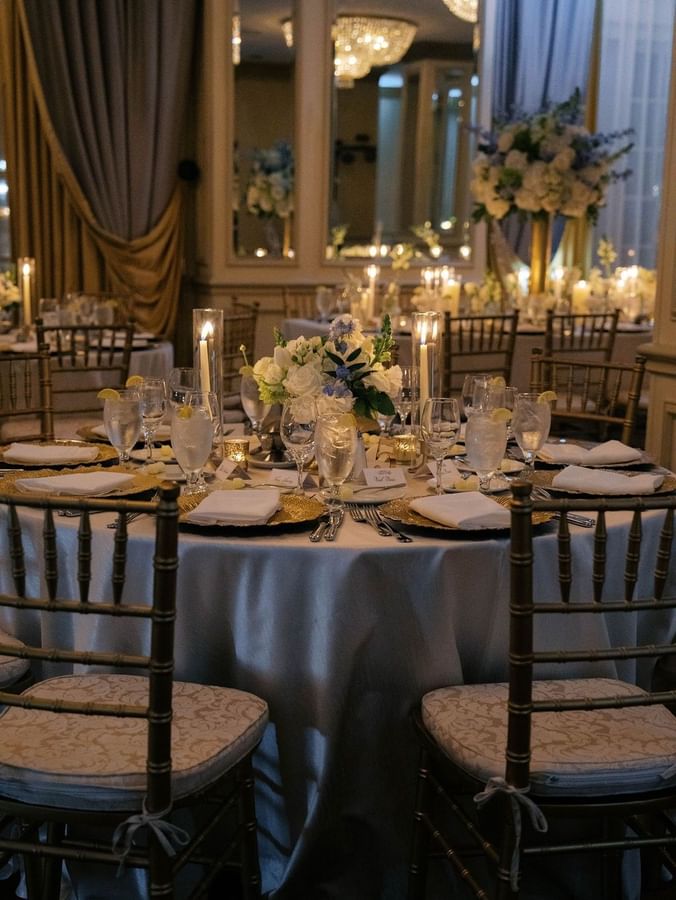 Candles by white florals on a round table under soft light for a dinner at Warwick Melrose Dallas