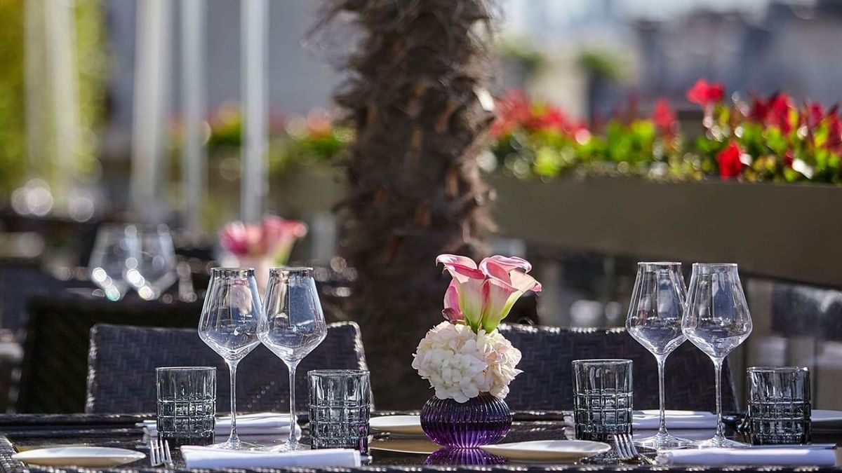 Wine glasses and a floral centerpiece by pink chairs under soft lighting at Warwick Paris Champs Elysées