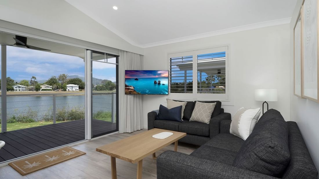 Deluxe Bungalow 2 Bedroom living area with sofas, wooden coffee table, lamp, and a TV at Mercure Hotel Townsville