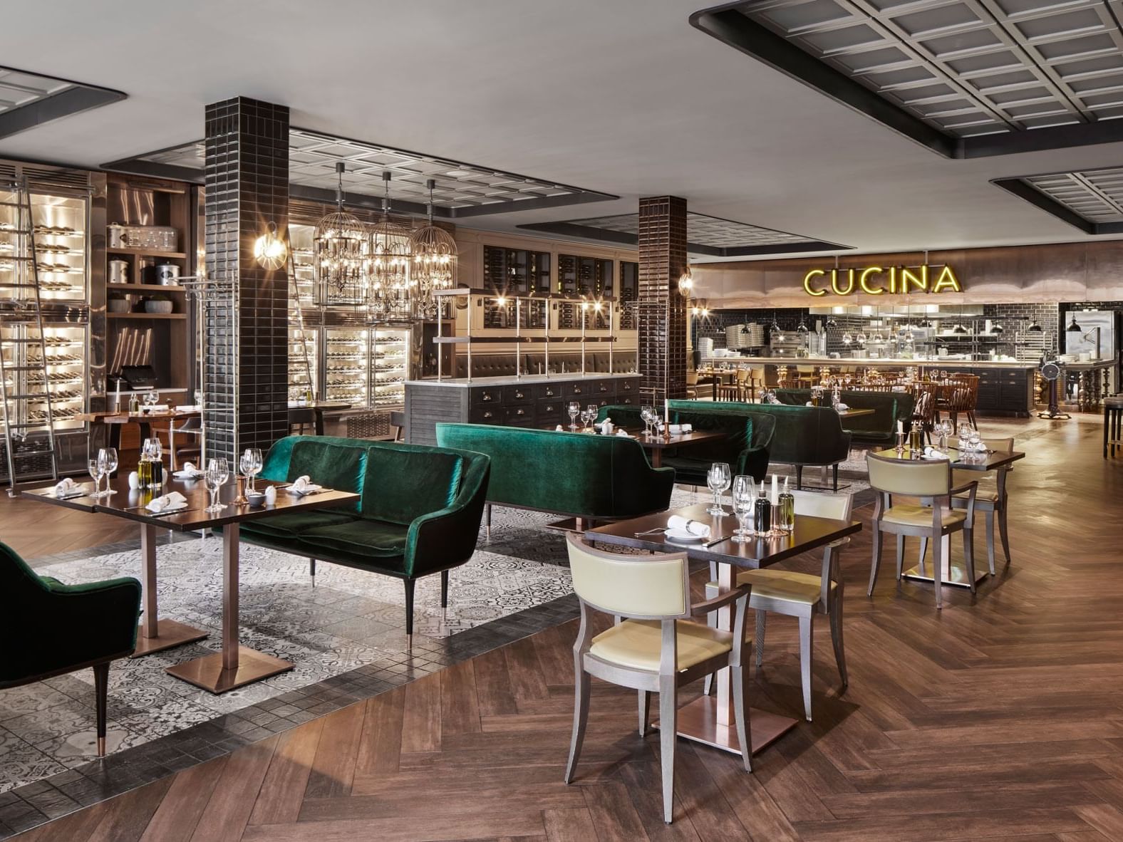 Elegantes Restaurant mit grünen Samtmöbeln, Holzboden, beleuchteten Kronleuchtern und stilvollen Regalen – Titanic Chaussee Berlin.