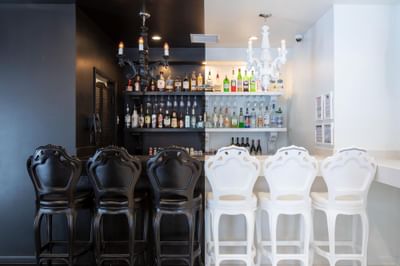 The Crooked Cabana Cafe with black and white high chairs and liquor bottles on shelves at The Roxbury