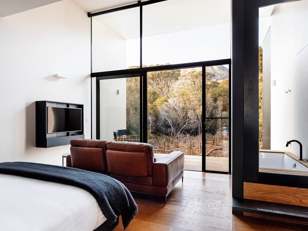 Sofa by the cozy bed in Mountain Terrace King with wooden floors at Freycinet Lodge