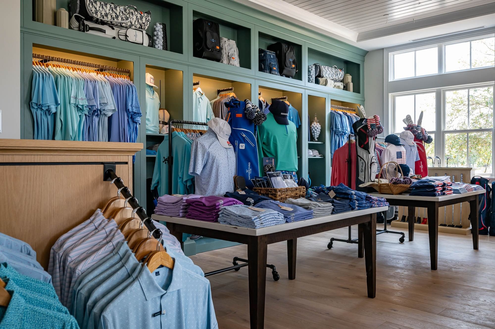 Store with shirts, caps, and golf bags displayed at the Camp Creek Golf Outfitter Shop.