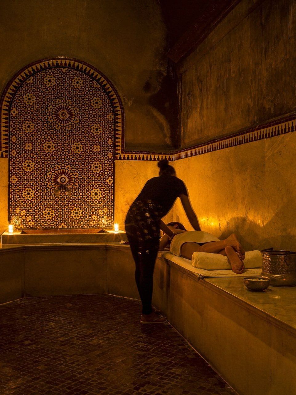 Woman having a body massage in Hammam by marocMaroc with lit candles at Selman Marrakech
