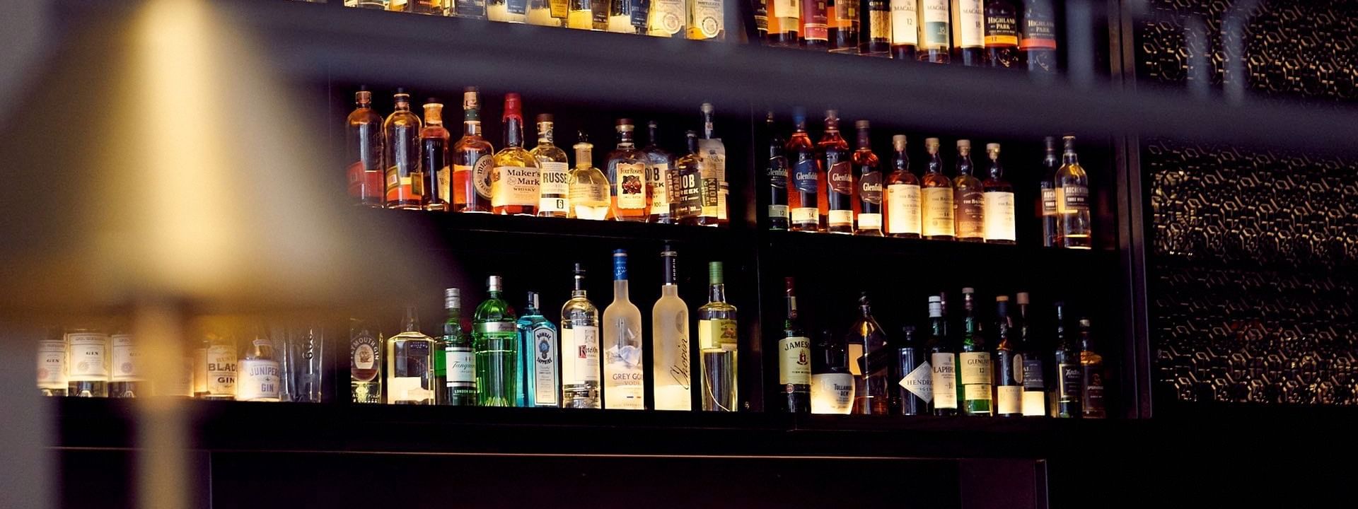 The European features Liquor bottles on backlit shelves by rows of wine glasses at Warwick San Francisco