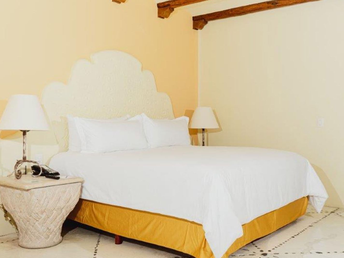 King Master Suite featuring a king bed, ornate white headboard, and warm yellow lighting at Quinta Real Huatulco