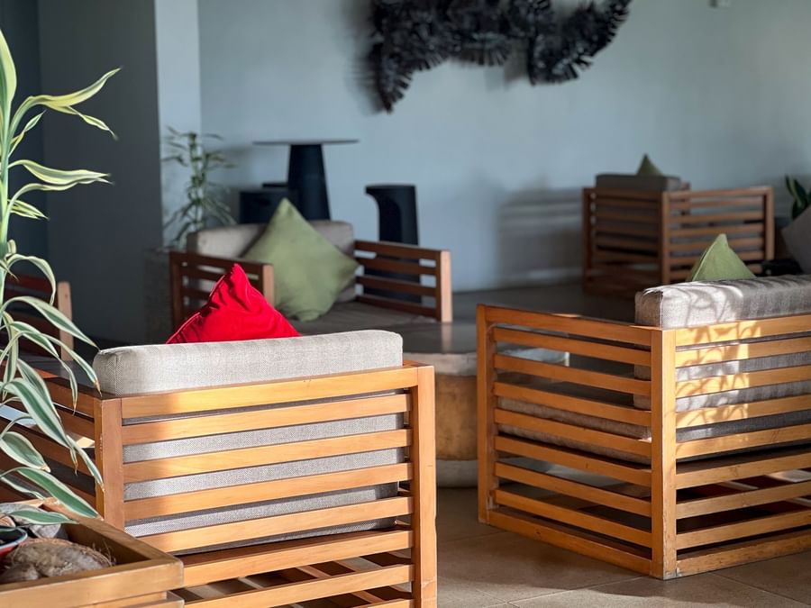 Lounge area with wooden slat chairs and colorful pillows by a plant at TokaToka Resort Nadi Fiji
