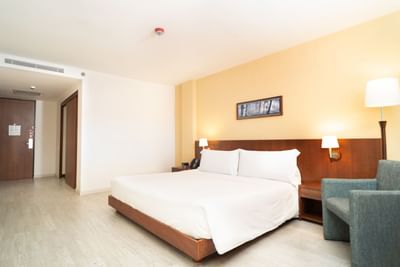 Standard Triple room with a cozy bed, armchair, perfect accommodation in bogota, and a bedside table at Habitel Hotel Select