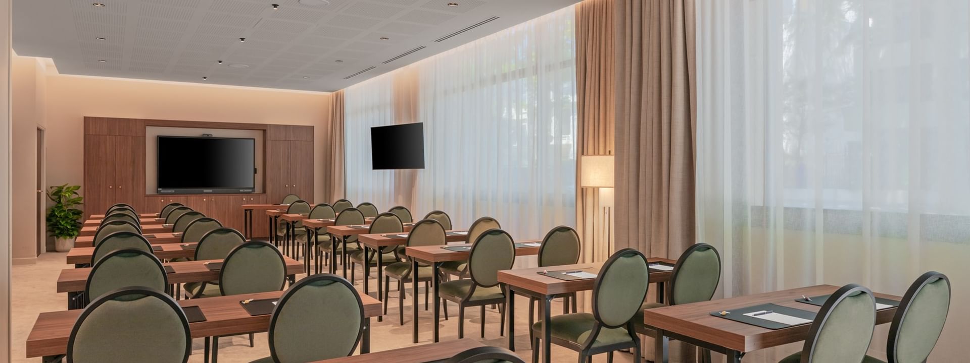 Classroom set-up with wall-mounted TV and cozy seating in the Astrid Salon at Warwick Reine Astrid - Lyon