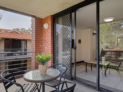 Outdoor balcony with table, chairs, and potted plant at UniLodge at Curtin University - Erica Underwood House.