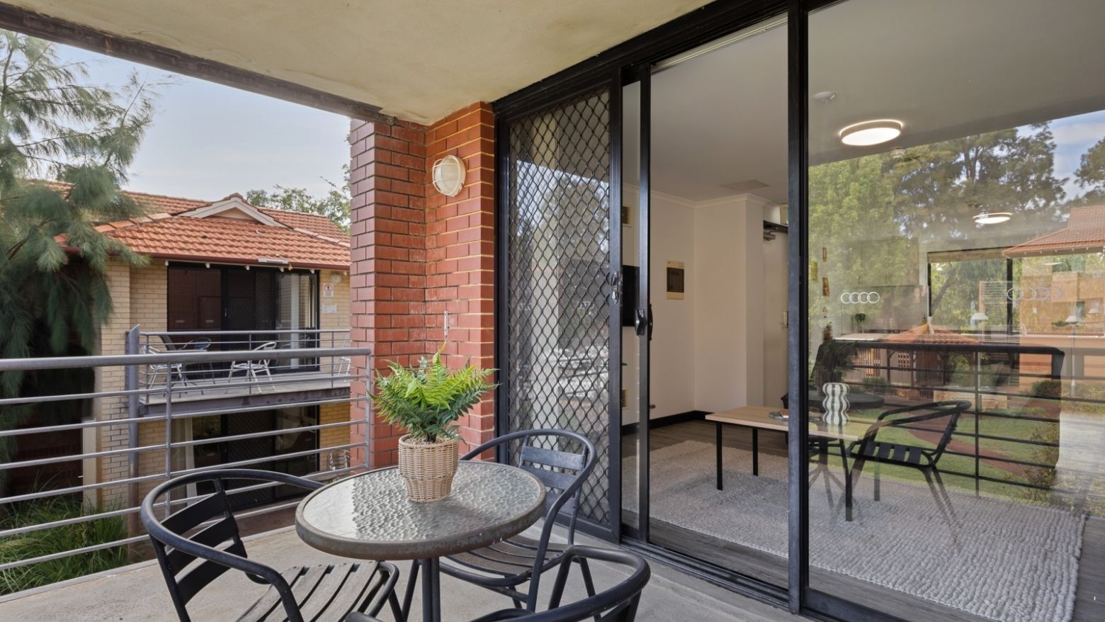 Outdoor balcony with table, chairs, and potted plant at UniLodge at Curtin University - Erica Underwood House.