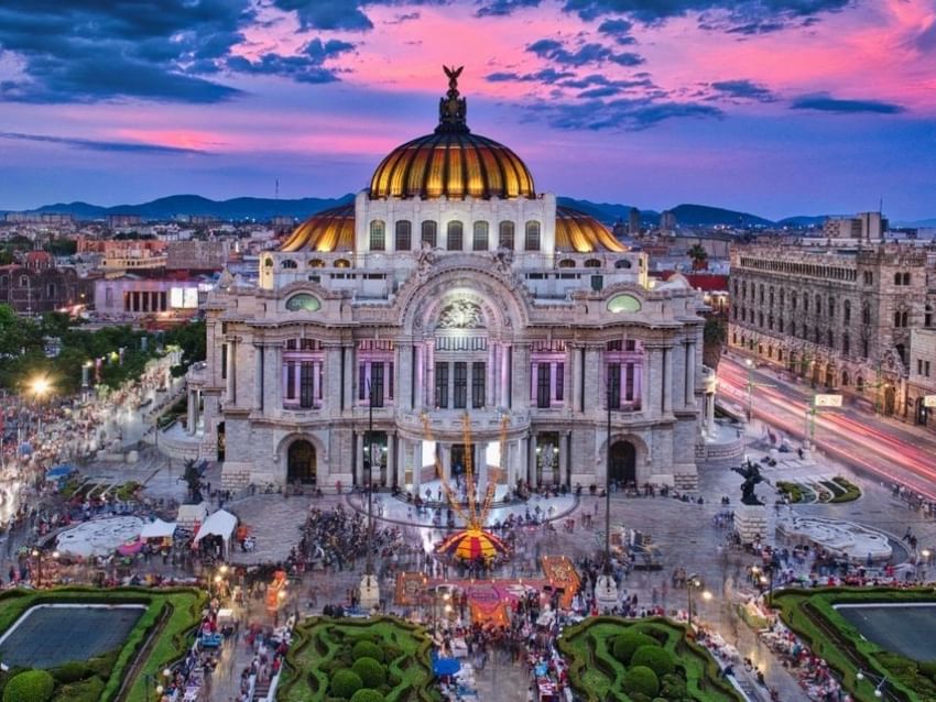 Palacio de Bellas Artes en Ciudad de México iluminado al atardecer bajo cielo rosa cerca de Camino Real