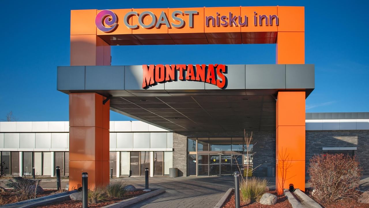 Front entrance of Coast Nisku Inn & Conference Centre with clear blue sky above.