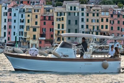 A boat moored in the harbor with colorful Italian buildings in the background at Grand Hotel Portovenere