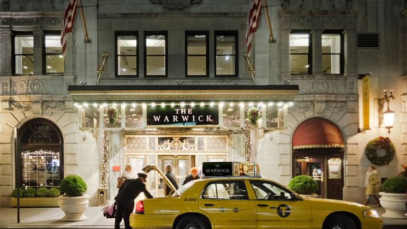 Warwick Melrose Hotel Dallas Ballroom entrance adorned with festive decorations, featuring a taxi and holiday spirit
