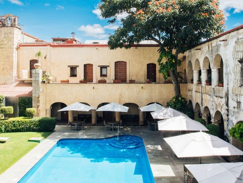 Historic courtyard with arched stone architecture surrounds a rectangular pool at Alberca Salon in Quinta Real Oaxaca