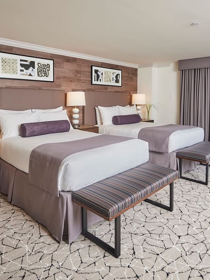 Deluxe Rooms feature twin beds by striped benches under a wood wall at Warwick Denver