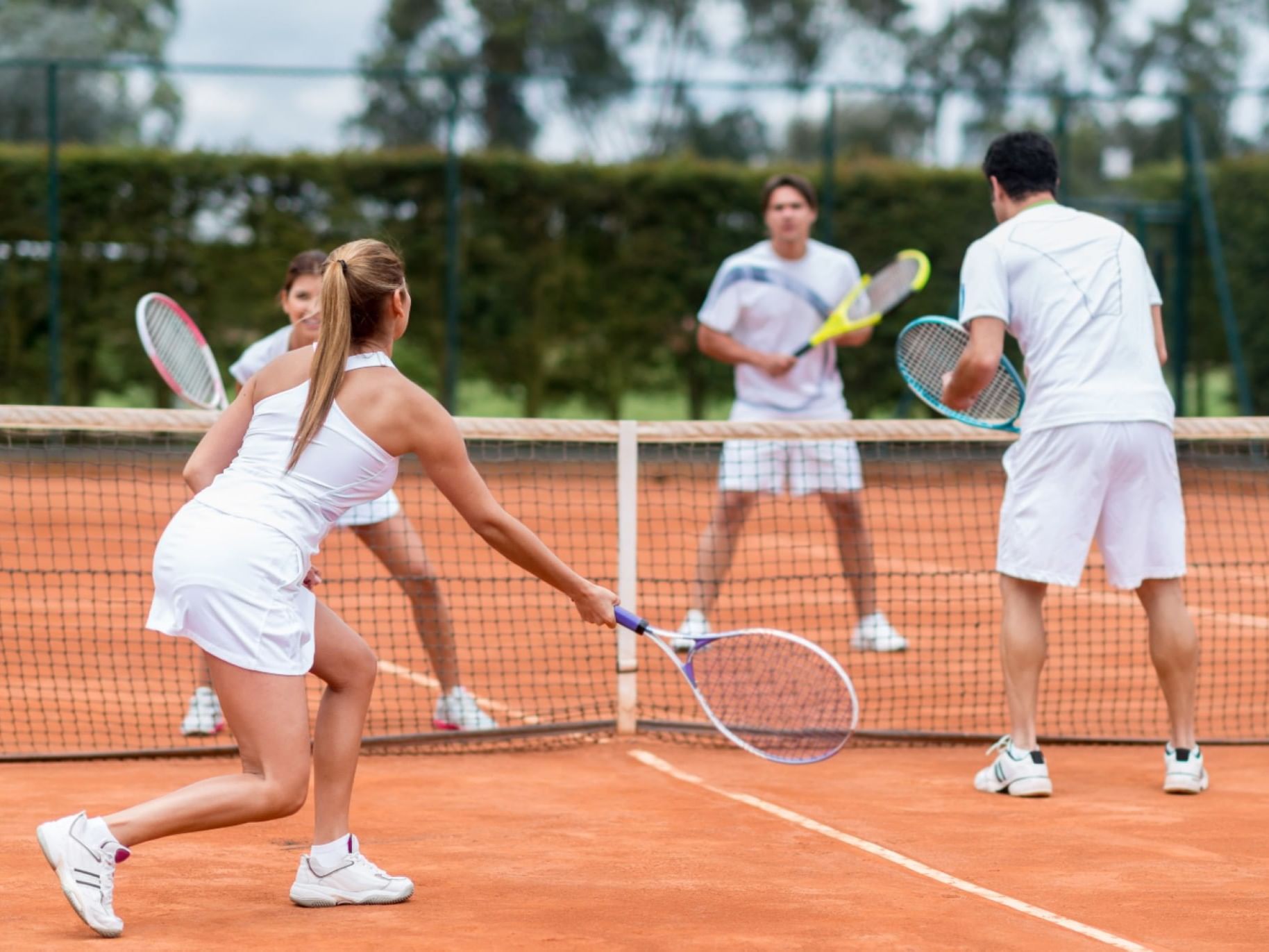 Four tennis players playing on a clay court at The Bethel Inn Resort & Suites