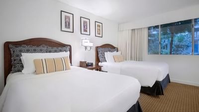 Two cozy beds with carpeted floors in Standard ADA Rooms 301 and 303 at Pavilion Hotel