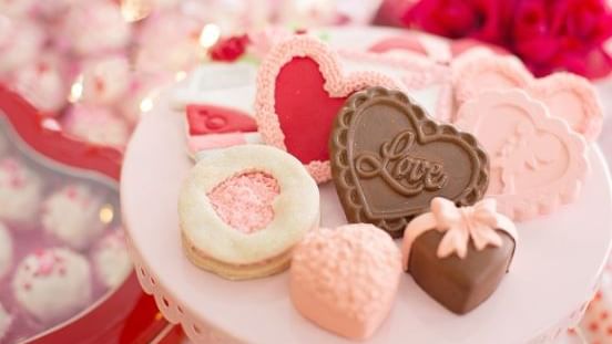 Heart-shaped chocolates and cookies on a stand for the Little Sweetheart Package.