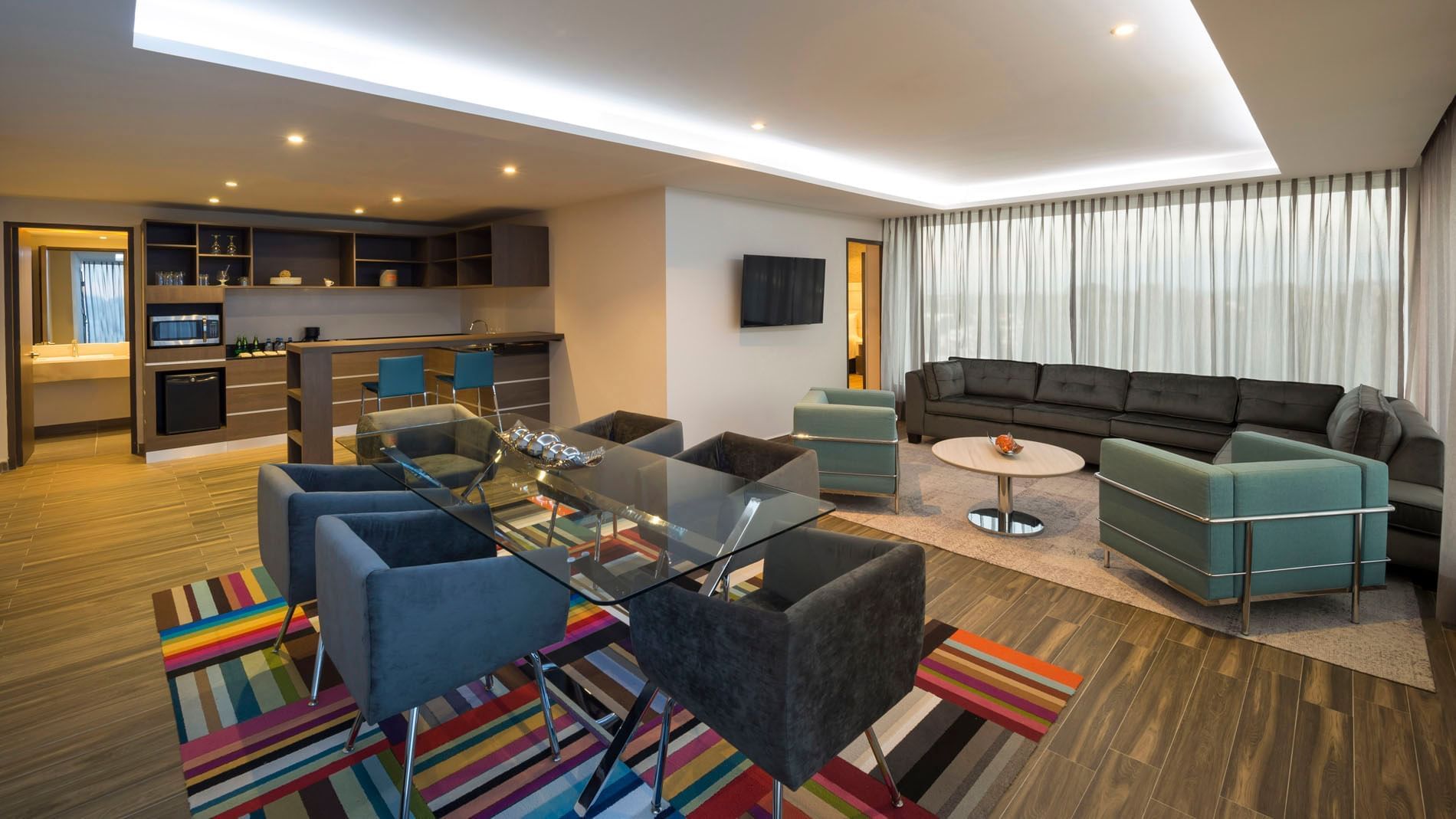 Spacious King Presidential Suite featuring a colorful rug, glass table, and plush lounge seating at Real Inn Celaya