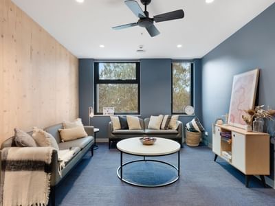 Modern living room with couches, coffee table, and ceiling fan at La Trobe University - North and South Apartments.