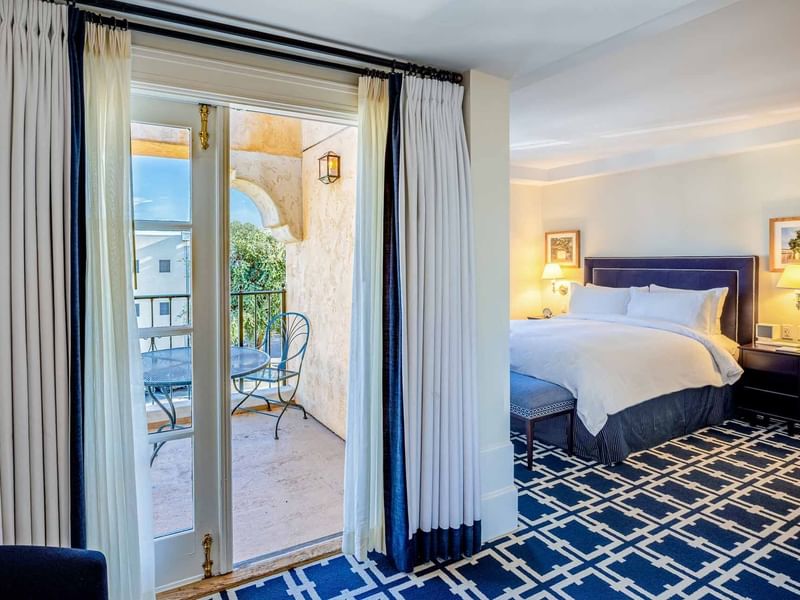 Deluxe Queen Room with a private balcony, large bed, and bold blue patterned carpet at El Prado Hotel
