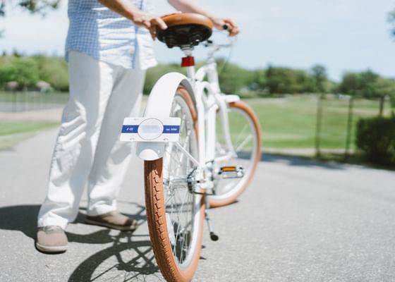 Man standing by a white bike with a parking tag attached at Gorges Grant Hotel