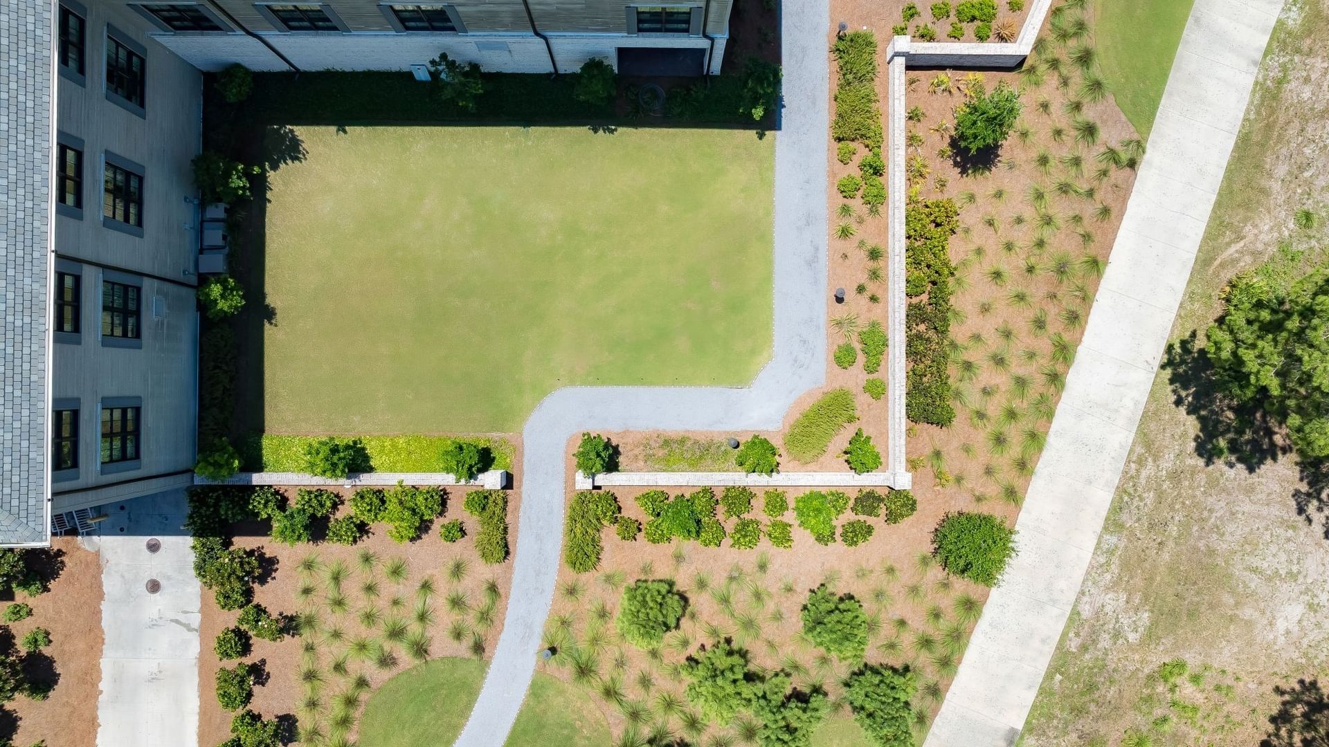 Aerial view of Magnolia Lawn with manicured grass, winding pathways, and landscaped grounds at Camp Creek Inn in Inlet Beach.