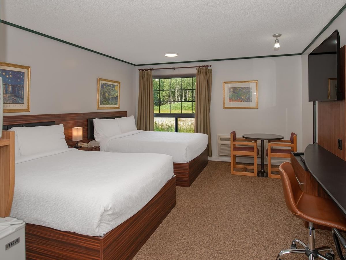 Guest room with two queen beds, work desk, TV and window