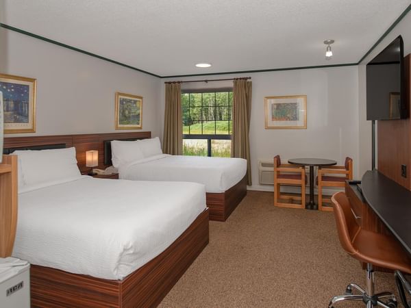 Guest room with two queen beds, work desk, TV and window