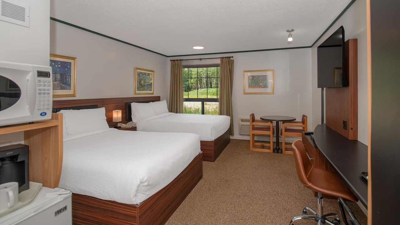 Guest room with two queen beds, work desk, TV and window