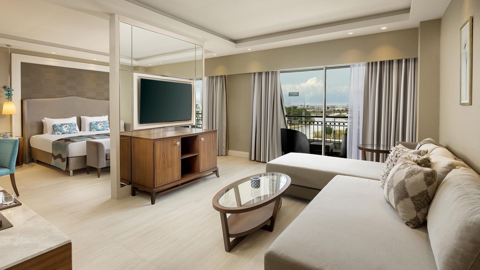 Deluxe room with sofa, TV, and balcony at Titanic Deluxe Golf Belek in Antalya.